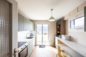 a kitchen with white cabinets and a large window at Chalet Les Tourelles in Aix-les-Bains