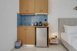 a kitchen with a sink and a refrigerator next to a bed at Seaview Double Room Private Jacuzzi in Santorini
