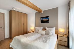 a bedroom with a large white bed with two lamps at Ciasa Irene Dreizimmerwohnung in La Villa
