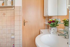a bathroom with a sink and a vase of flowers at Reichenaublick in Allensbach