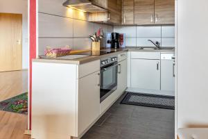 a kitchen with white cabinets and a stove at Terrassenpark Schonach App 161 in Schonach +19 photos