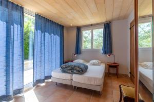 a bedroom with two beds and blue curtains at Le Serre Du Puech in Chambonas +26 photos