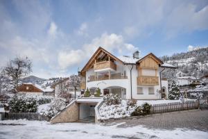 a large white house with snow on the ground at Ciasa Tlara App Lisa in San Vigilio Di Marebbe