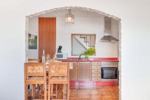 an arched doorway into a kitchen with red countertops at Casa Roque in Haría