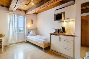 a room with a bed and a kitchen with a sink at Altes Schulhaus in Heiligenberg