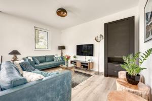 a living room with blue couches and a tv at Casa Bos Schotsman Wellness in Kamperland