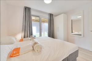 a bedroom with a large white bed with a window at Casa Bos Schotsman Wellness in Kamperland