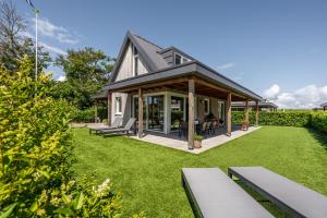 a house with a green yard with benches at Casa Bos Schotsman Wellness in Kamperland