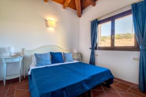 a bedroom with a bed with blue sheets and a window at Villa Giada in Stintino