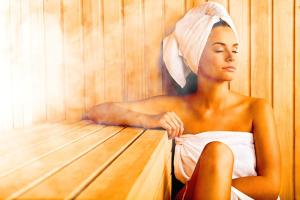 a woman sitting in a sauna with a towel on her head at Chalet Schlossberg Rosengarten in Nova Ponente