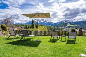 two chairs and an umbrella in the grass with mountains at Chalet Schlossberg Rosengarten in Nova Ponente