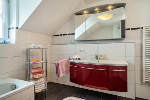 a bathroom with a sink and a red cabinet at Storchennest in Markdorf +17 photos