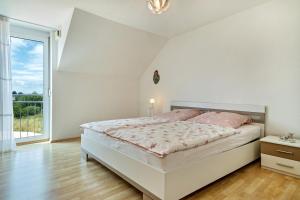 a white bedroom with a bed and a large window at Storchennest in Markdorf