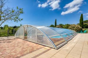 a glass greenhouse on a brick patio at Maison Abricot avec piscine in Aspiran
