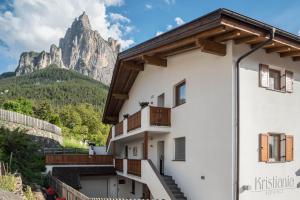a building with a mountain in the background at Kristiania Apartement Typ A2 in Siusi