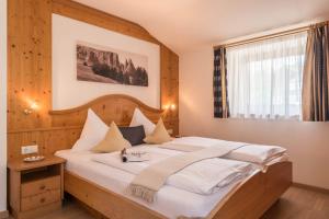 a bedroom with a large bed with a wooden headboard at Kristiania Apartement Typ A2 in Siusi