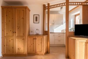 a kitchen with wooden cabinets and a tv in a room at Kristiania Apartement Typ A2 in Siusi