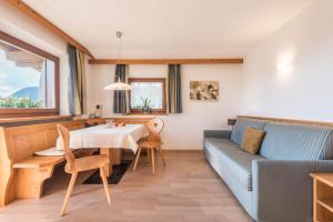 a living room with a table and a blue couch at Kristiania Apartement Typ A2 in Siusi
