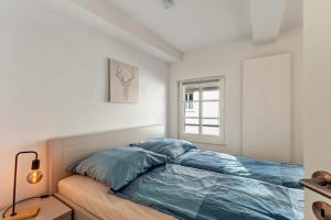 a bedroom with a bed with blue sheets and a window at alter Speicher in Warendorf