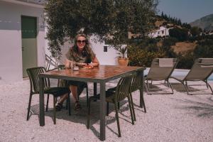 a woman sitting at a wooden table with chairs at Villa Bellido in Alora