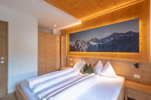 a bedroom with a white bed with a picture on the wall at Kriendl Nr 2 in Valdaora