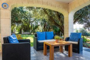 an outdoor patio with chairs and a table with blue pillows at Es Pujols in Artá