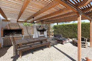 a wooden pergola with a picnic table and a grill at Monte do Tanoeiro - Casa da Barrica in Rogil