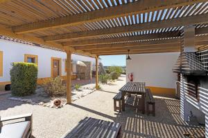 a patio with a wooden pergola and a picnic table at Monte do Tanoeiro - Casa da Barrica in Rogil