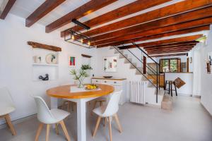a dining room with a wooden table and white chairs at La Fortaleza in Pollença