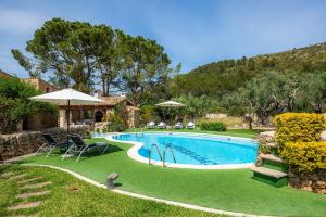 a swimming pool in a yard with chairs and umbrellas at La Fortaleza in Pollença