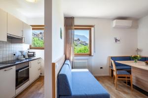 a small kitchen with a blue couch and a table at Gartenheim App Leonhard in Schenna