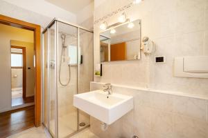 a white bathroom with a sink and a shower at Gartenheim App Leonhard in Schenna +14 photos