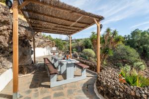 a patio with a table and chairs under a wooden pergola at Finca Toledo in San Miguel de Abona