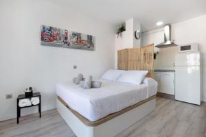 a white bedroom with a bed and a kitchen at Apartamento Saltillo Alto in Torremolinos