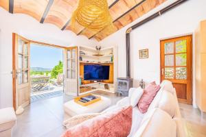 a living room with a white couch and a tv at Els Abats in Fornalutx