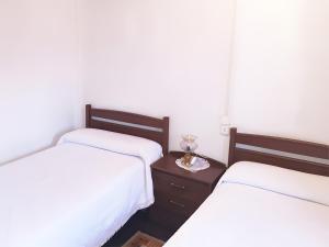 two beds in a room with white sheets and a table at Posada Rural La Capellanía in Celis