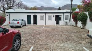 a car parked in front of a white house at De Kothuize 10 in Graaff-Reinet