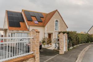 a house with solar panels on the roof at Courseulles Comme À La Maison in Courseulles-sur-Mer