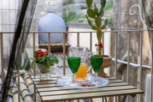 a table with glasses and a drink on a balcony at Dimora D'Incanto in Ragusa