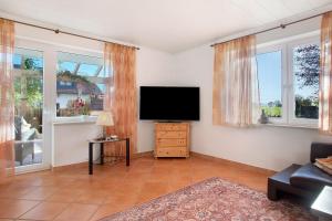 a living room with a flat screen tv and windows at Haus Blaulichtfamilie in Opfenbach