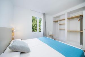 a white bedroom with a bed with a blue blanket at Apartament Massanet 1a in Canyamel