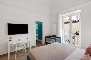 a bedroom with a bed and a desk and a television at Lubrense Signature Suites in Massa Lubrense