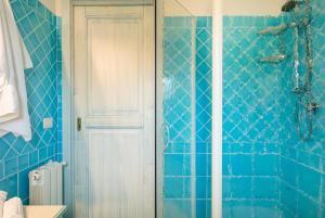 a blue tiled bathroom with a shower and a door at Bia de Bados B5 in Olbia