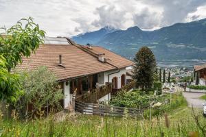 a house on a hill with mountains in the background at Apartment Ida - Obermösslhof in Lana