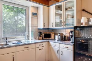 a kitchen with white cabinets and a sink and a window at Haus Hafenblick in Walchum