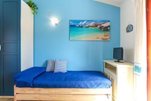 a blue room with a bed and a television at Bilocale Geranium Beach in San Teodoro
