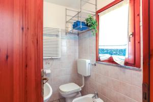 a bathroom with a toilet and a sink and a window at Bilocale Geranium Beach in San Teodoro +18 photos