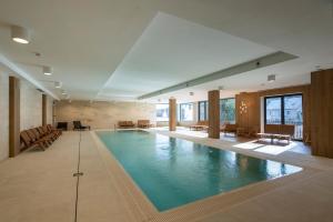 a large swimming pool in a large room with chairs and tables at Resort Aurum in Černý Dŭl