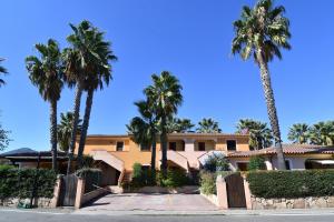 a building with palm trees in front of a street at Bilocale Geranium Beach in San Teodoro
