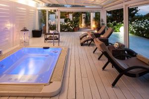 a hot tub on a deck with chairs and a pool at Tenuta Del Poggio Antico in Ischia